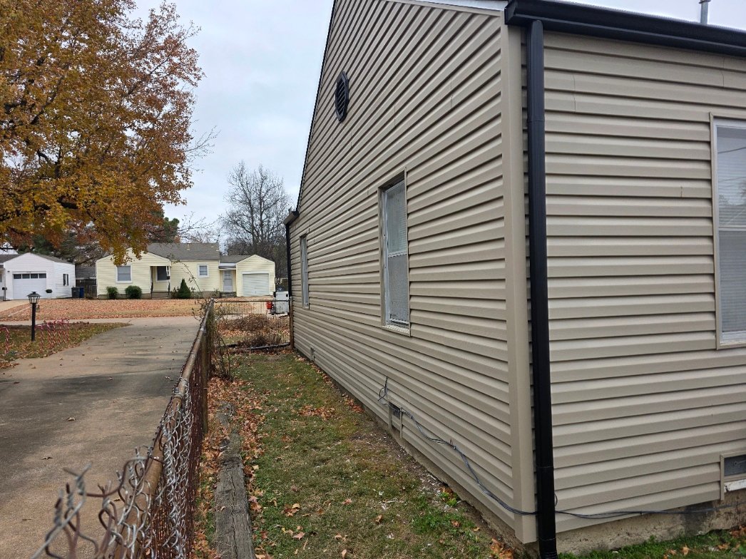 Fascia metal installed behind vinyl siding with siding butted tight to the metal at the roof edge on a Tulsa home